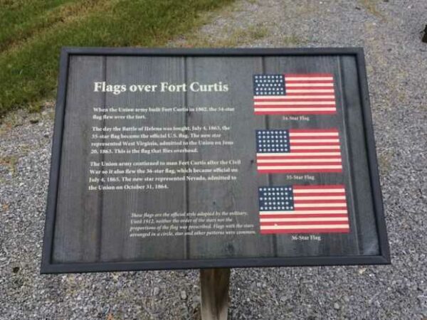 FLAGS OVER FORT CURTIS MEMORIAL PLAQUE