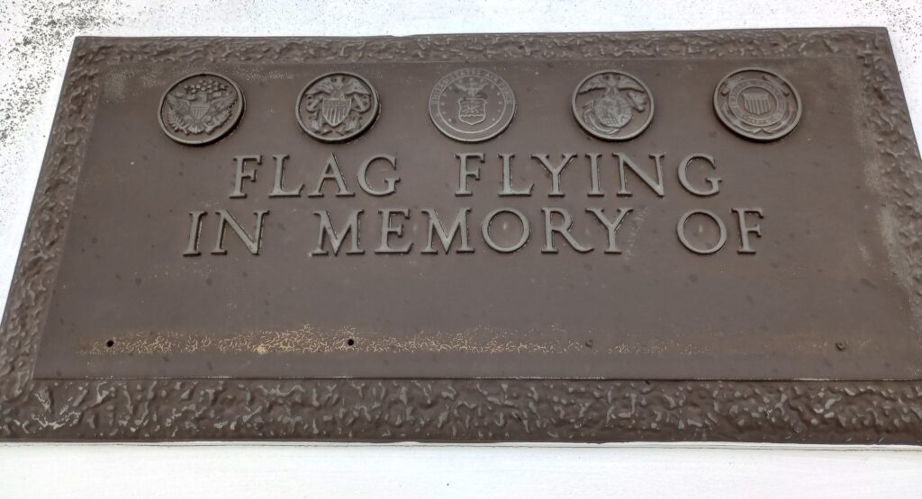 FLAG FLYING IN MEMORY OF MEMORIAL PLAQUE