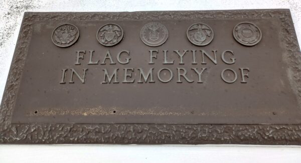 FLAG FLYING IN MEMORY OF MEMORIAL PLAQUE